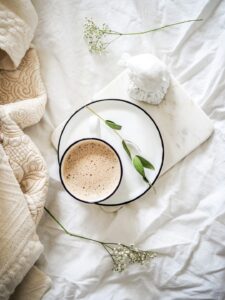 An adult sitting comfortably by a window with a mug and a journal, looking outside on a cold day.