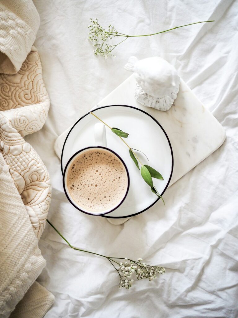 An adult sitting comfortably by a window with a mug and a journal, looking outside on a cold day.